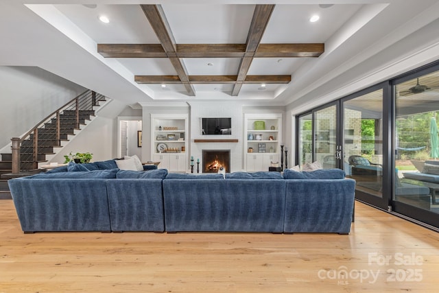 living room with coffered ceiling, beamed ceiling, light wood-style floors, built in shelves, and stairway