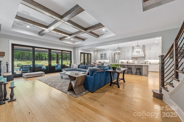 living area featuring stairway, light wood-style flooring, coffered ceiling, and beamed ceiling