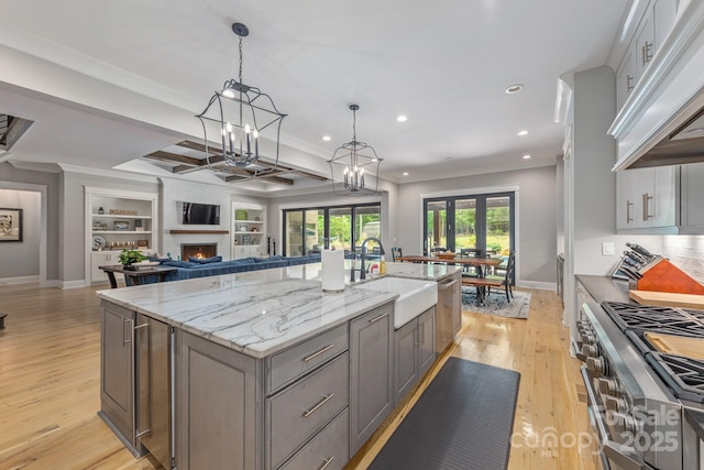 kitchen with recessed lighting, stainless steel appliances, under cabinet range hood, light wood finished floors, and a sink