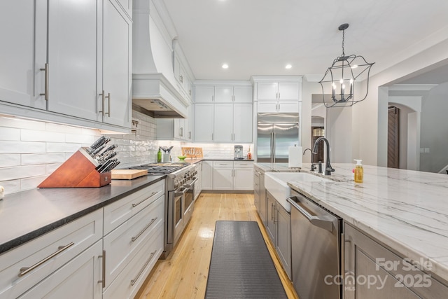 kitchen featuring a sink, arched walkways, recessed lighting, custom exhaust hood, and high end appliances