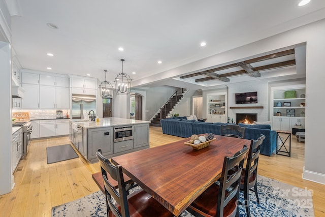 dining area featuring recessed lighting, stairway, beamed ceiling, a large fireplace, and light wood-type flooring
