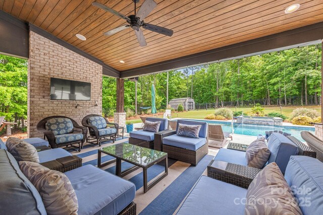 view of patio / terrace with an outdoor structure, an outdoor living space, ceiling fan, a fenced backyard, and a storage shed