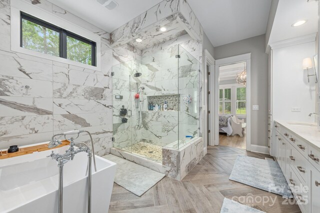 ensuite bathroom with recessed lighting, ensuite bathroom, vanity, a soaking tub, and a marble finish shower