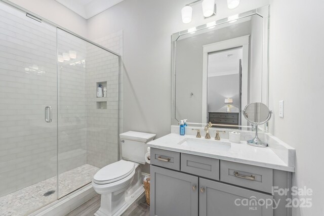 full bath featuring a stall shower, toilet, wood finished floors, and vanity