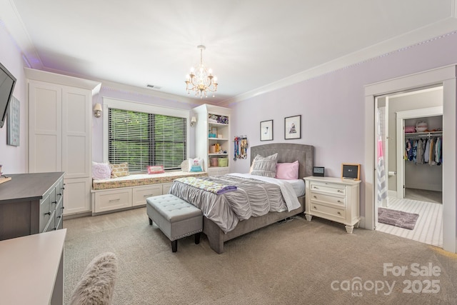 bedroom with an inviting chandelier, light carpet, a walk in closet, visible vents, and crown molding