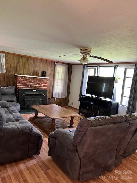 living room with a ceiling fan, wood finished floors, a healthy amount of sunlight, and wooden walls