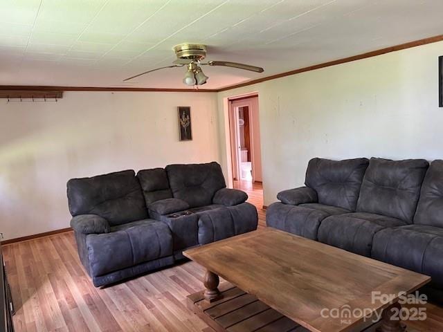 living area with ornamental molding, light wood finished floors, ceiling fan, and baseboards