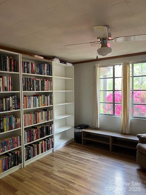 sitting room featuring wall of books and wood finished floors