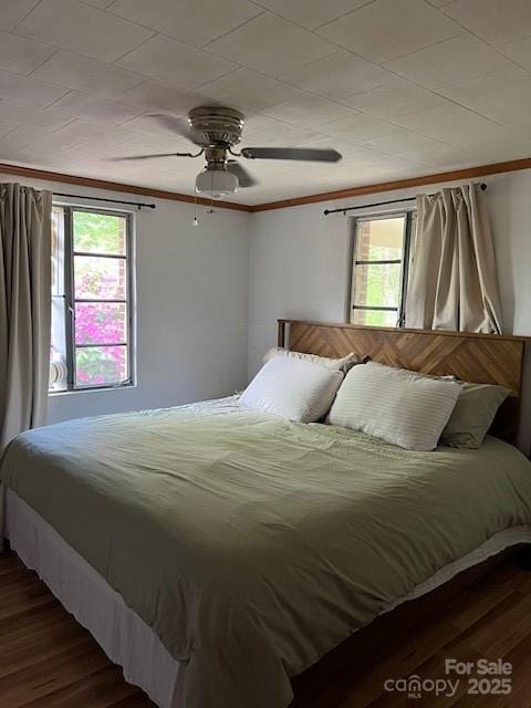 bedroom featuring wood finished floors, multiple windows, and crown molding