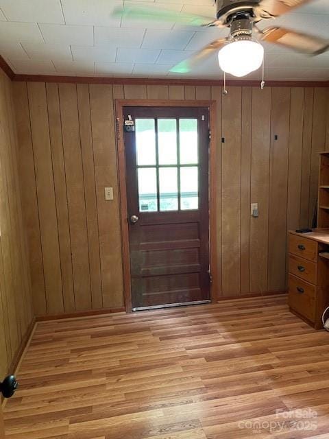 doorway to outside with a ceiling fan, wooden walls, and light wood finished floors