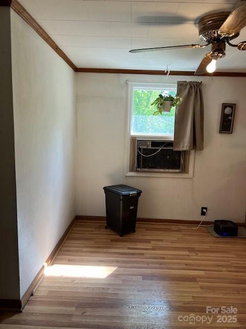 spare room with cooling unit, ceiling fan, light wood finished floors, baseboards, and crown molding