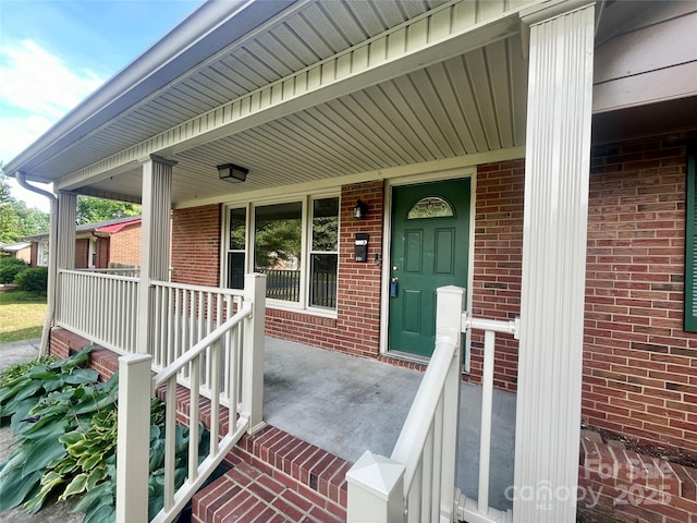 property entrance with covered porch and brick siding