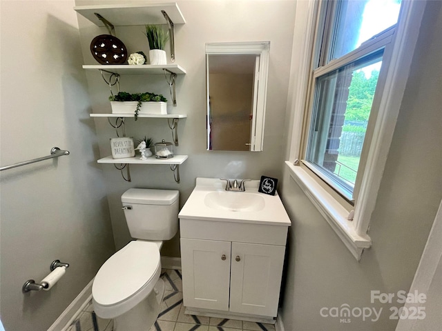 half bathroom with toilet, tile patterned flooring, vanity, and baseboards