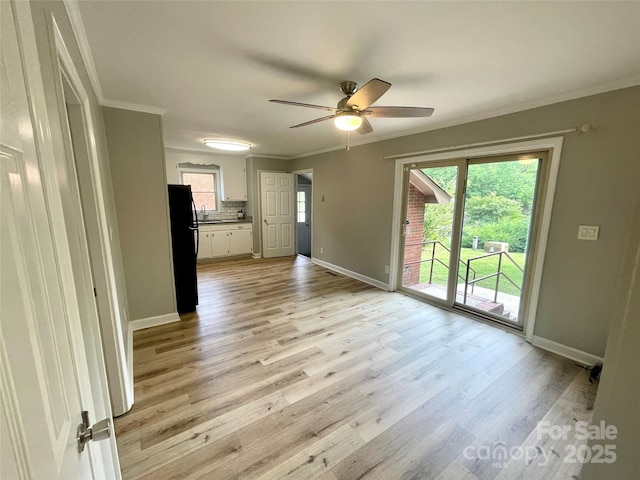 unfurnished living room featuring light wood-style floors, ceiling fan, a healthy amount of sunlight, and baseboards