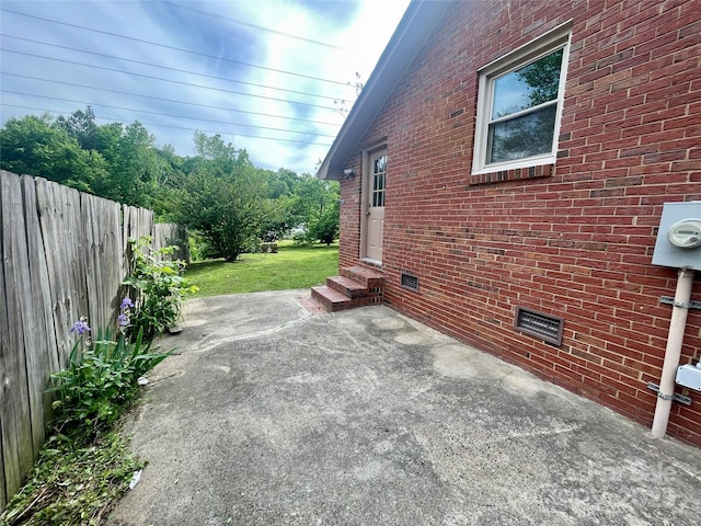 view of home's exterior with brick siding, fence, a patio, entry steps, and crawl space