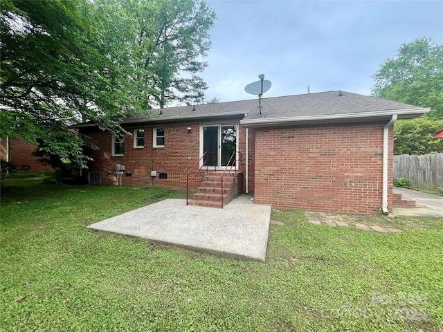back of house with fence, a patio, entry steps, a lawn, and brick siding