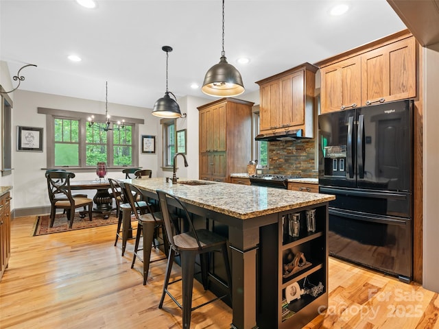 29 Ravenna St, Asheville, NC 28803 - kitchen with black fridge, a sink, under cabinet range hood, decorative backsplash, and light stone countertops