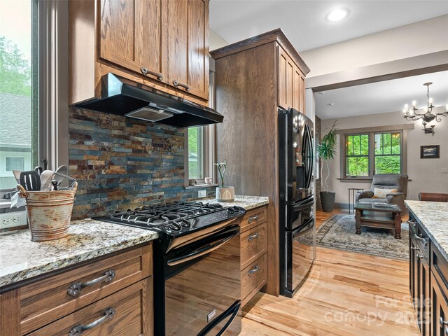 29 Ravenna St, Asheville, NC 28803 - kitchen with black appliances, under cabinet range hood, open floor plan, tasteful backsplash, and light wood-style floors