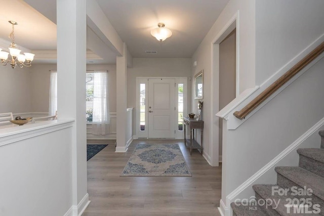 entrance foyer featuring plenty of natural light, stairway, wood finished floors, and a chandelier
