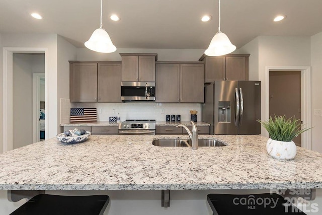 kitchen featuring tasteful backsplash, a sink, appliances with stainless steel finishes, a spacious island, and a breakfast bar