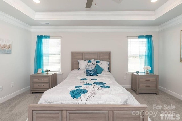 bedroom with multiple windows, a tray ceiling, and light carpet