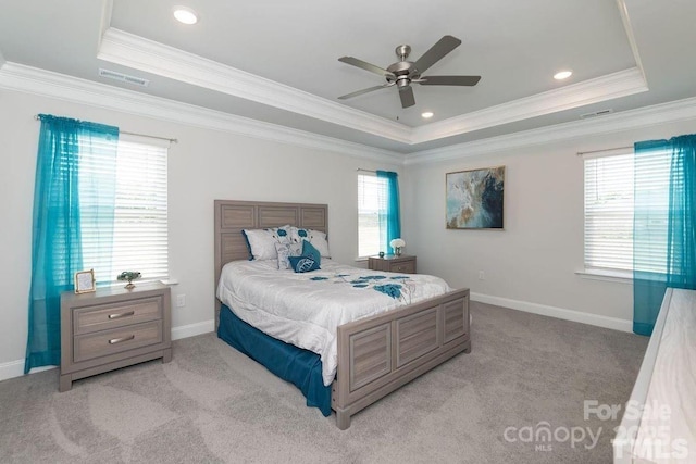 carpeted bedroom with visible vents, a raised ceiling, ornamental molding, and multiple windows