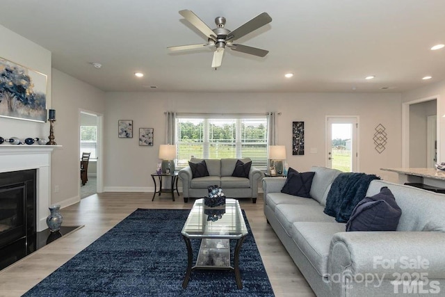 living room with recessed lighting, a ceiling fan, and light wood-style flooring