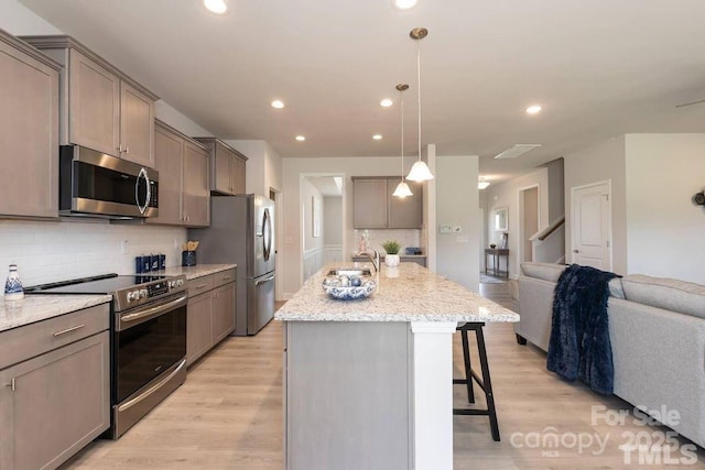 1479 Mocksville Hwy Unit 23, Statesville, NC 28625 - kitchen with appliances with stainless steel finishes, open floor plan, a breakfast bar, tasteful backsplash, and an island with sink