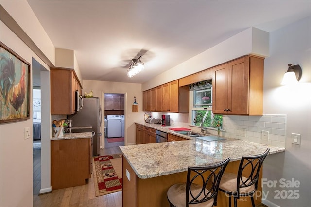 597 Sweetwater Rdg, Burnsville, NC 28714 - kitchen with a peninsula, stainless steel appliances, washer / clothes dryer, light wood finished floors, and a breakfast bar