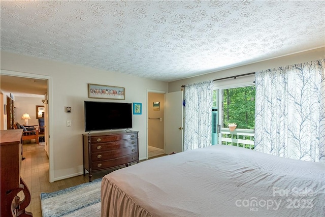597 Sweetwater Rdg, Burnsville, NC 28714 - bedroom featuring wood finished floors, a textured ceiling, and access to exterior