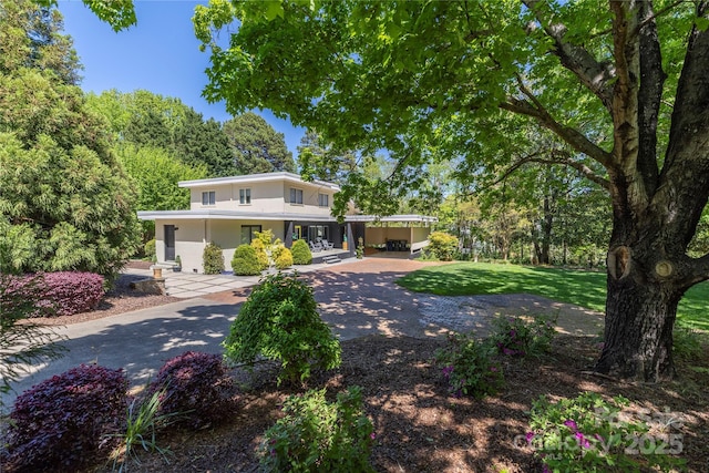 view of front facade featuring concrete driveway, a front yard, and stucco siding