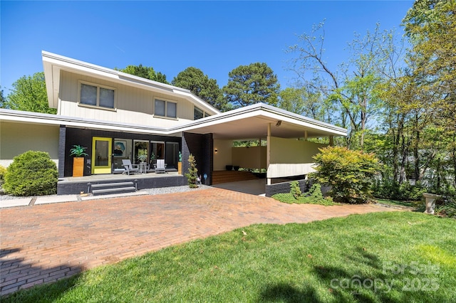 rear view of property featuring brick siding, a porch, and a yard