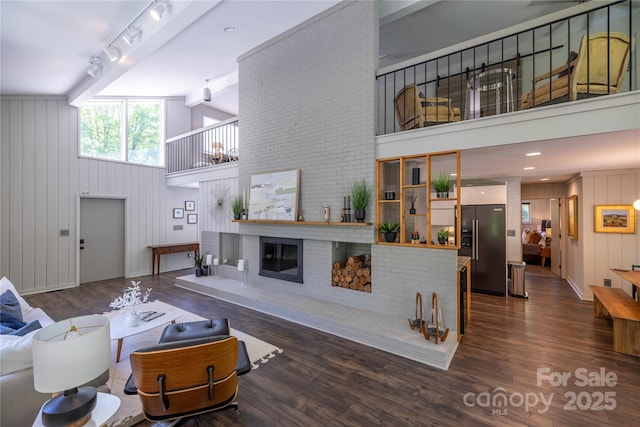 living area featuring dark wood finished floors, baseboards, a fireplace, and a towering ceiling