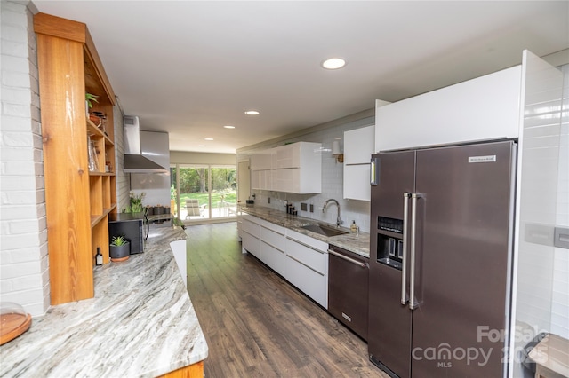 kitchen featuring dark wood-style floors, a sink, stainless steel appliances, wall chimney exhaust hood, and white cabinetry