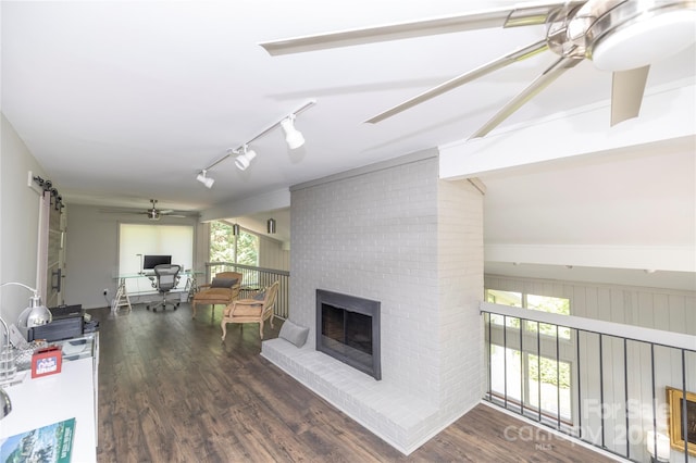 living area featuring a fireplace, wood finished floors, a ceiling fan, and rail lighting