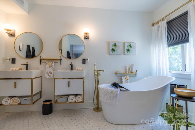 bathroom featuring tile patterned floors, two vanities, a sink, baseboards, and a soaking tub
