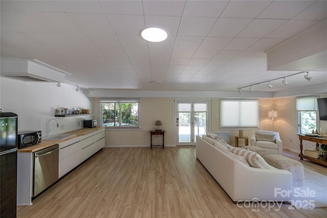 living area with track lighting, brick wall, and light wood-type flooring