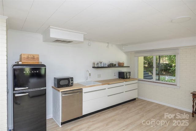 kitchen with a sink, light wood-style floors, rail lighting, black appliances, and white cabinets