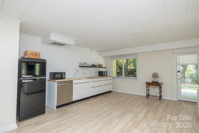 kitchen with black appliances, a healthy amount of sunlight, light wood-style floors, and brick wall
