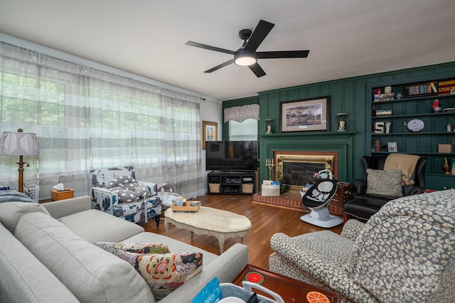 living area featuring a fireplace, a ceiling fan, and wood finished floors