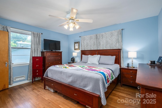 bedroom featuring a ceiling fan, visible vents, and wood finished floors