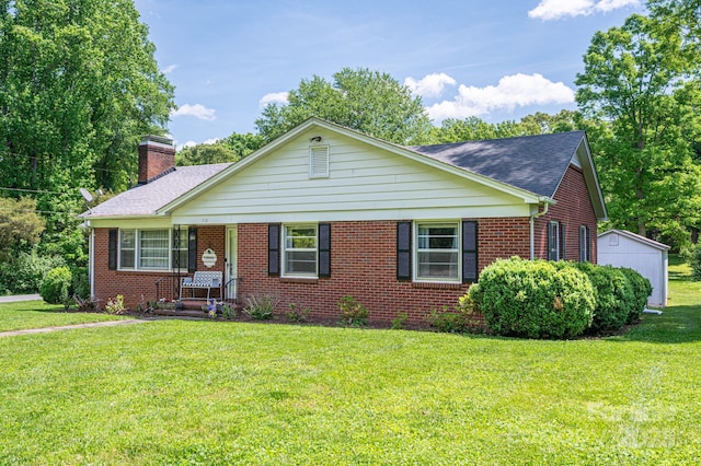 ranch-style home with roof with shingles, a front lawn, brick siding, an outbuilding, and a chimney