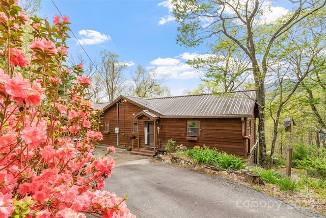 rustic home with driveway and metal roof