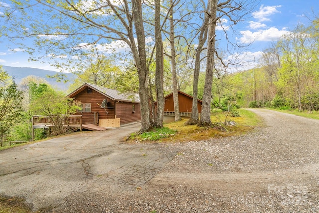 view of home's exterior featuring a deck with mountain view and aphalt driveway