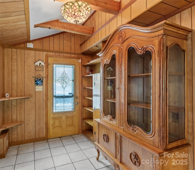 mudroom with wood walls, lofted ceiling, and light tile patterned floors