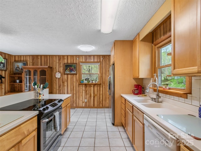 kitchen featuring a sink, appliances with stainless steel finishes, wood walls, and light countertops