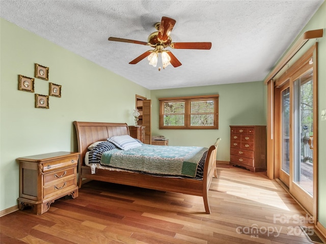 bedroom featuring light wood-style floors, a textured ceiling, baseboards, and access to outside