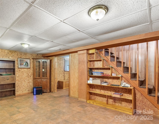 below grade area with stairway, baseboards, and a paneled ceiling