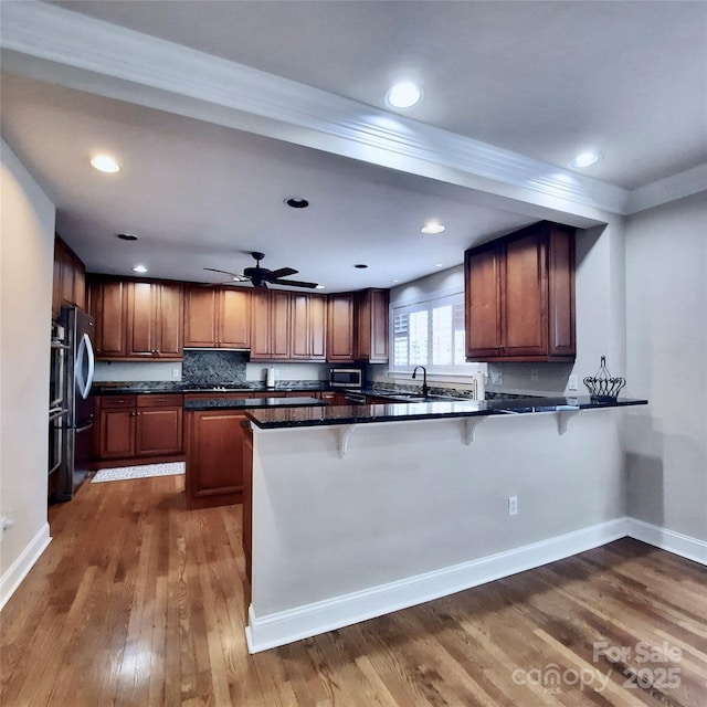 kitchen featuring a breakfast bar, dark wood-type flooring, dark countertops, and freestanding refrigerator