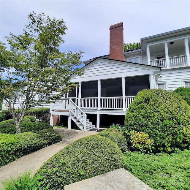 view of front of house with a sunroom, stairs, and a chimney